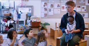 White Teacher Speaks to Children With a Black Non-Binary Doll